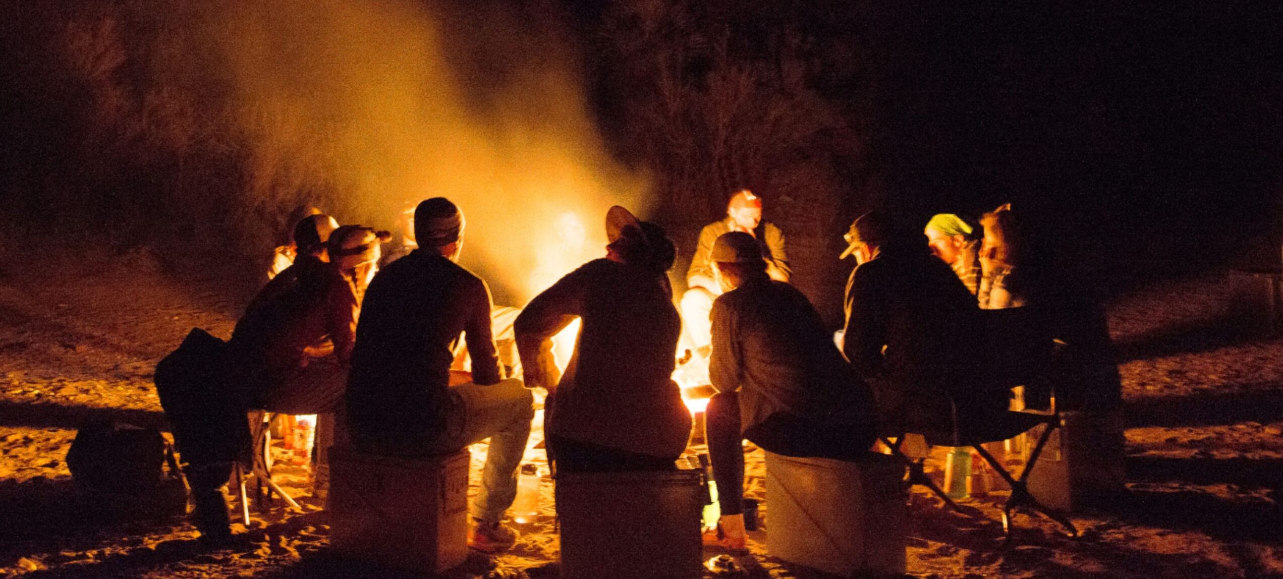 People sit around a campfire along the salt river in arizona